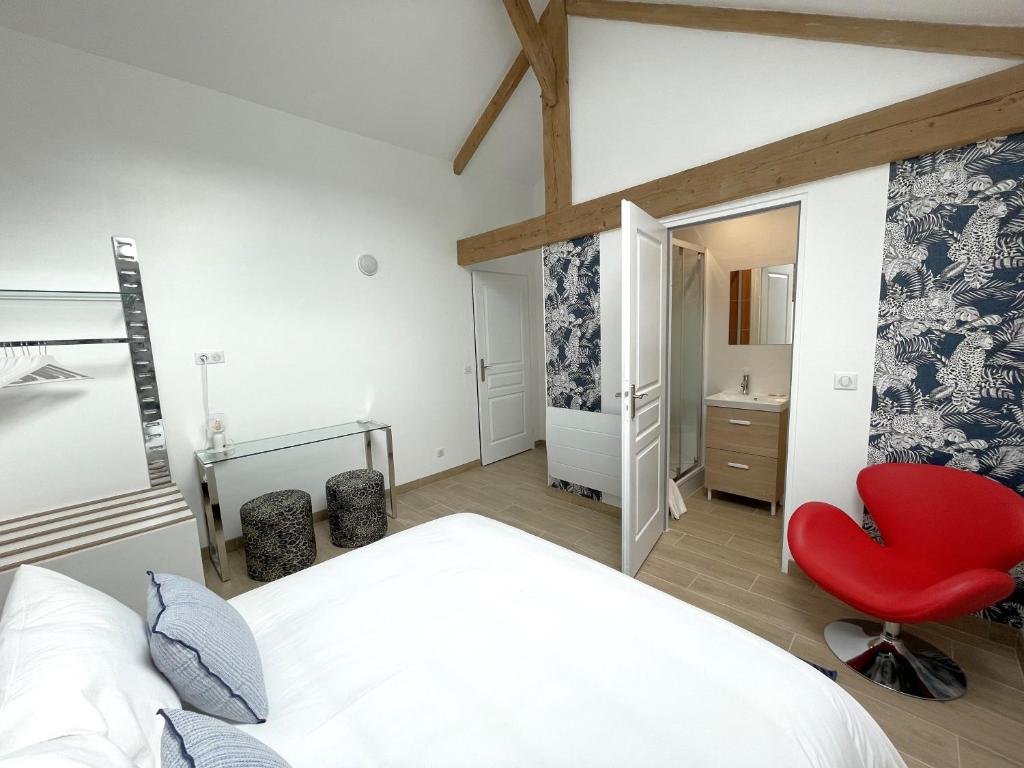 una camera con un letto bianco e una sedia rossa di Le Relais de 40 Sous a Aubergenville
