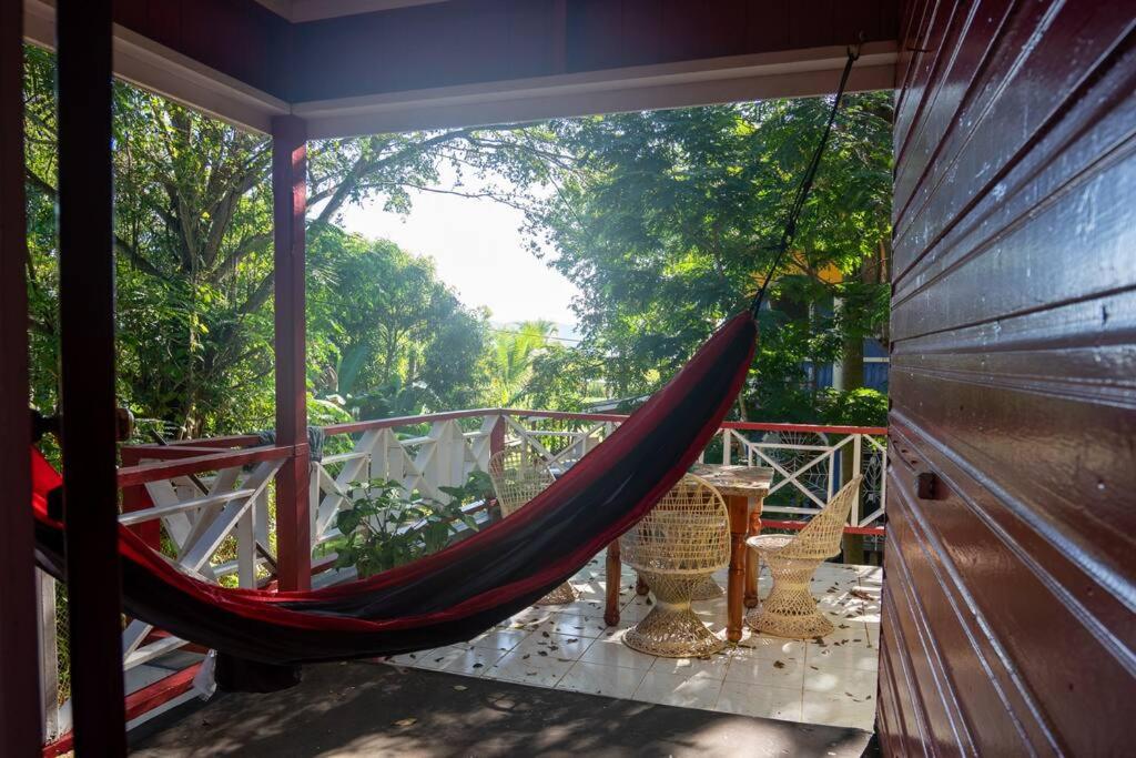 a hammock on a porch with chairs and trees at Relax in Paradise: Spectacular house In Negril-Indika in Negril