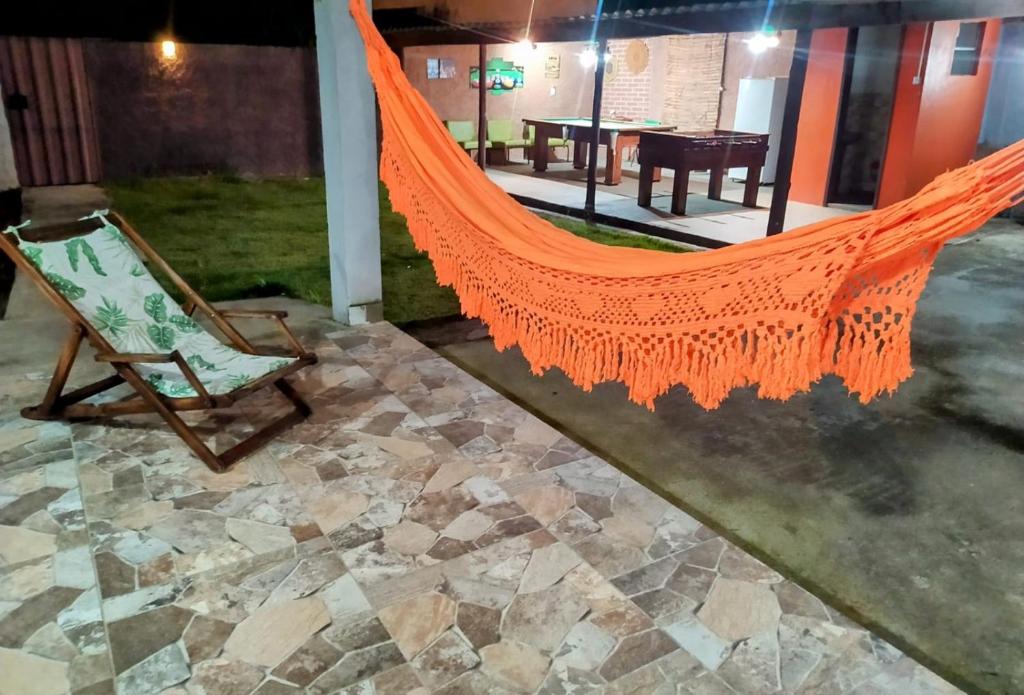 uma rede de descanso laranja num pátio com uma cadeira em Casa de campo Maria&Maria próximo a cidade de Juiz de Fora MG em Juiz de Fora
