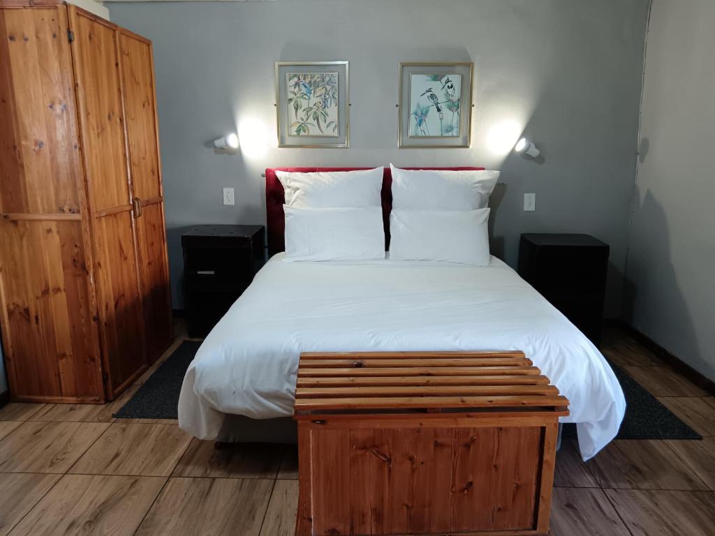 1 dormitorio con 1 cama grande y armario de madera en The Grey's Inn, en Machadodorp