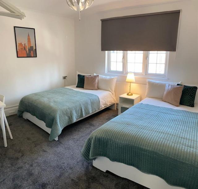 a bedroom with two beds and a window at CAMDEN TOWN PARKWAY ROOMS in London