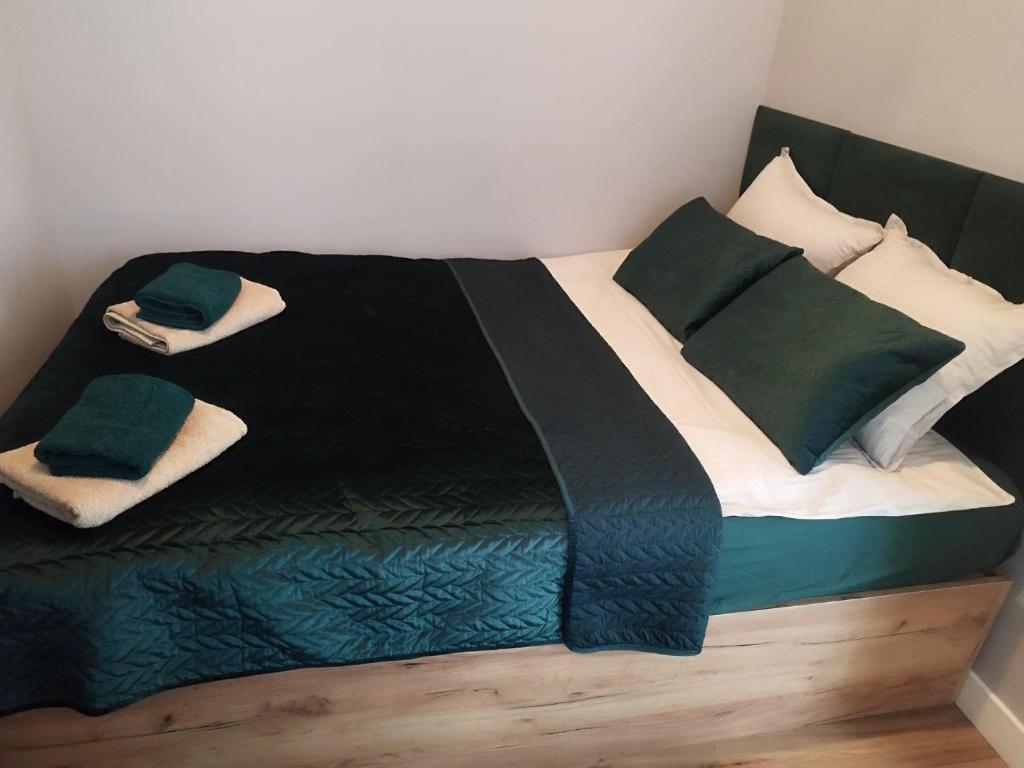 Cama con mantas y almohadas verdes y blancas en Nowy Apartament en Mińsk Mazowiecki
