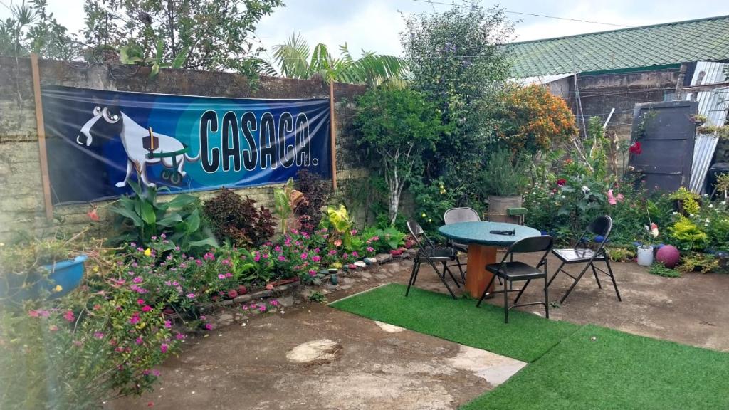 einen Garten mit einem Tisch, Stühlen und Blumen in der Unterkunft Casaca in Concepción de Ataco