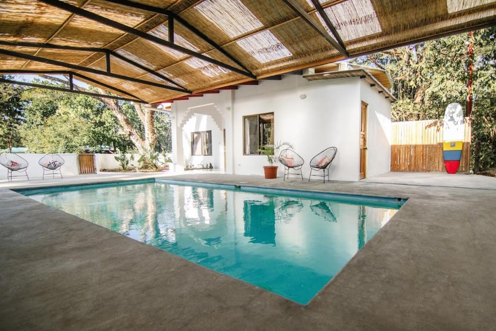 una piscina cubierta con sillas y una casa en Cocoon CoLive Nosara, en Nosara