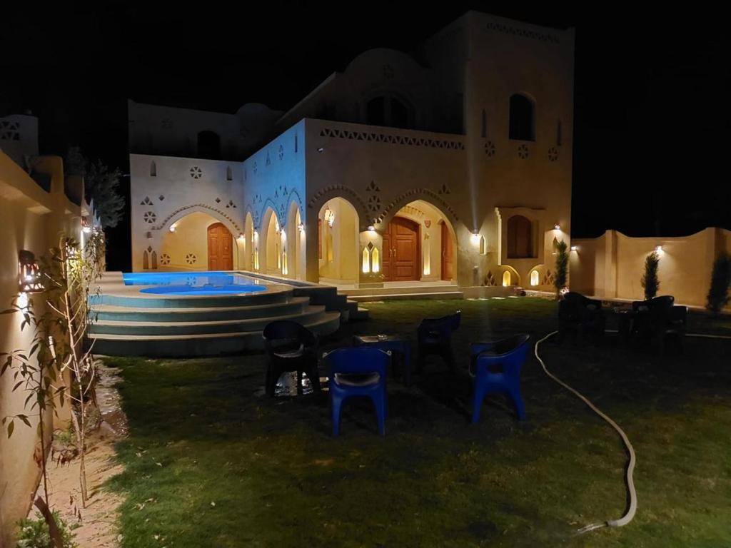 un edificio con un cortile con sedie blu e una piscina di فيلا الريف السويسري a Tunis