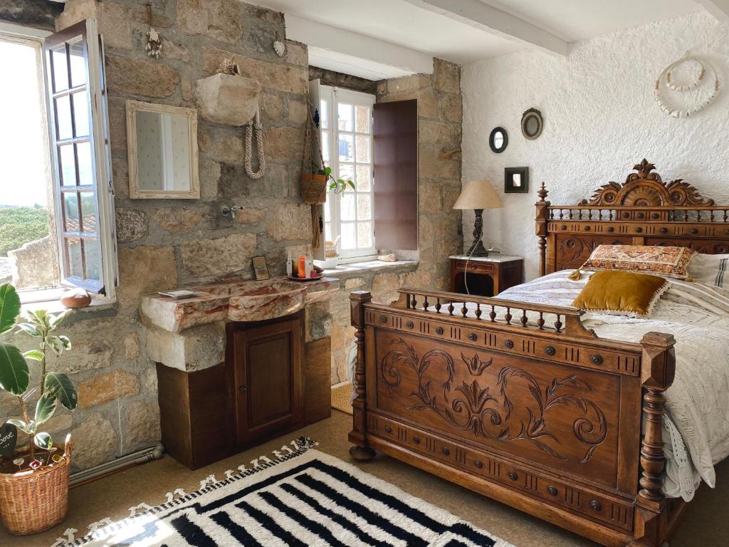 ein Schlafzimmer mit einem großen Bett und einer Steinmauer in der Unterkunft Le temps retrouvé Maison de village de charme in Caunes-Minervois