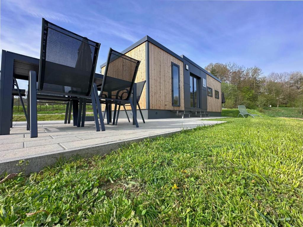 une maison avec une table et des chaises dans l'herbe dans l'établissement Feriendorf Seeblick - Tinyhouse direkt am See, à Neunburg vorm Wald