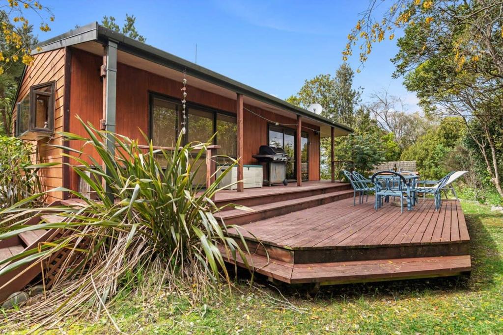 uma casa com um deque de madeira com uma mesa e cadeiras em Waters Edge Golden Bay em Collingwood