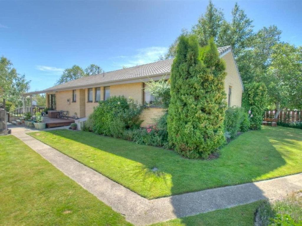 a house with a large tree in the yard at Kiwi Holidays in Cromwell in Cromwell