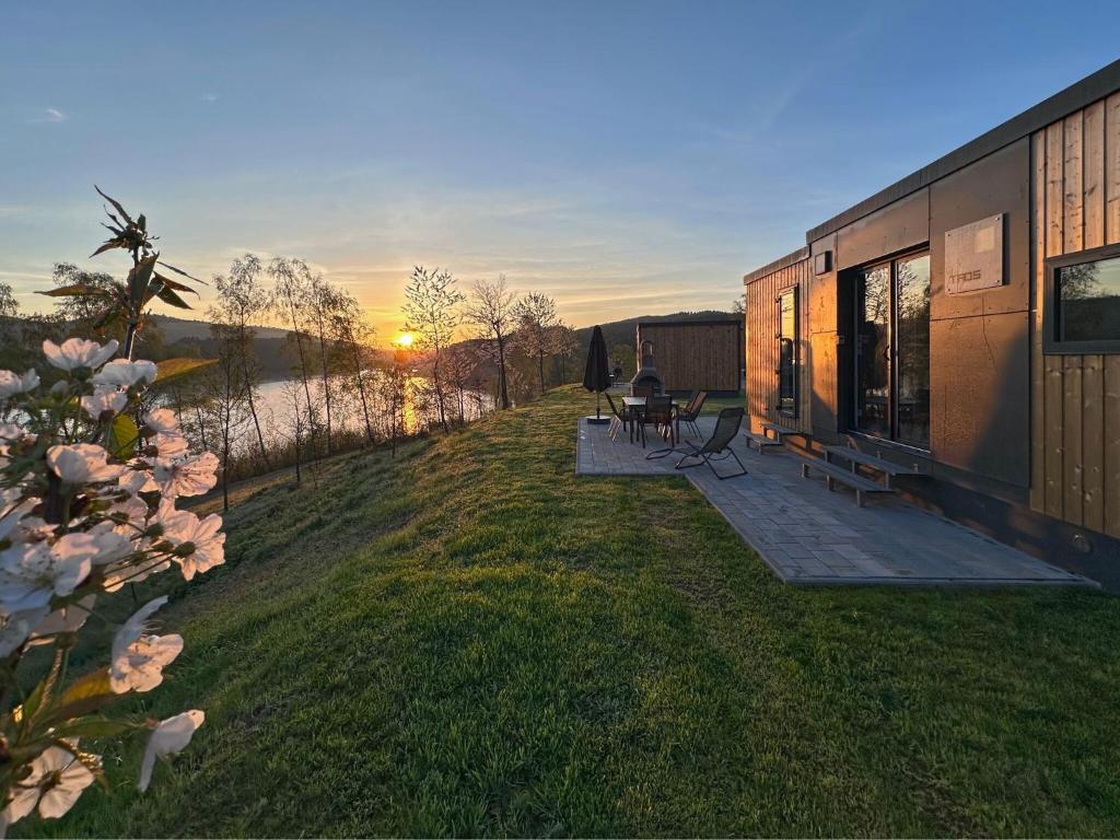 a house with a deck with a sunset in the background at Tiny house with lake view in holiday village in Bavaria in Neunburg vorm Wald