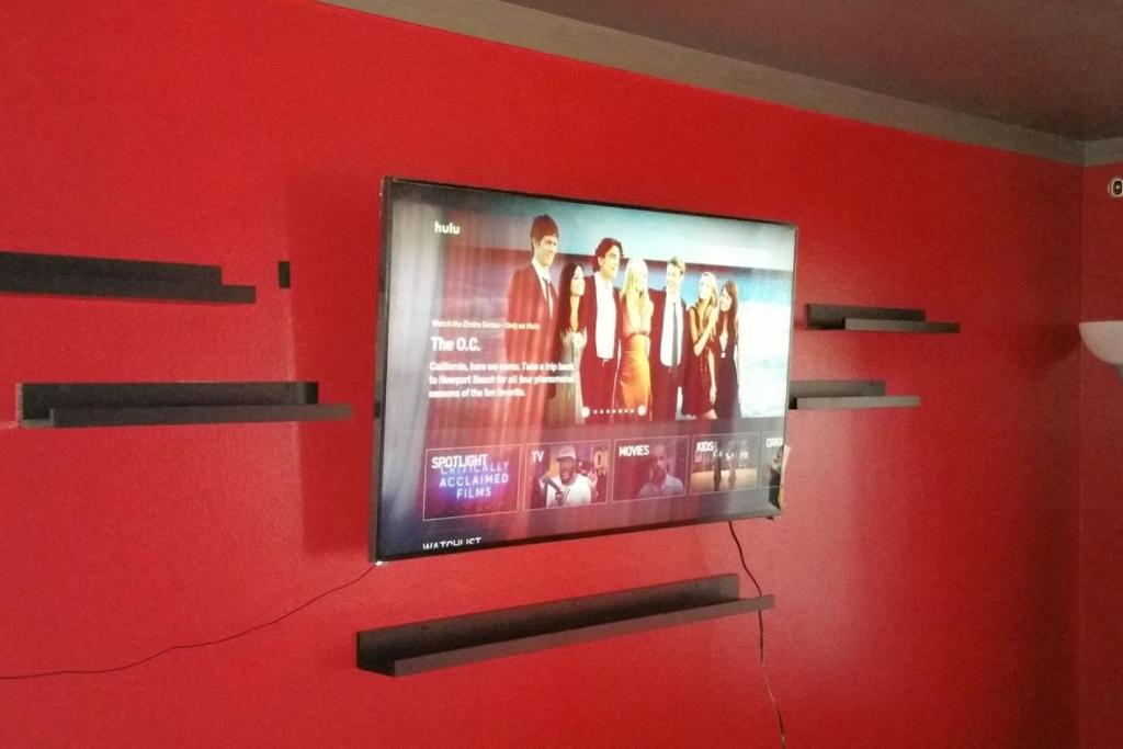 TV de pantalla plana colgada en una pared roja en Dallas Private Room 6, en Dallas