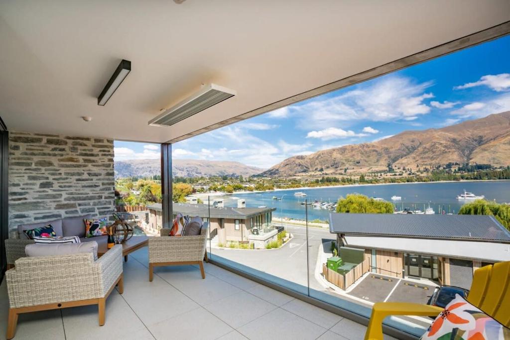a living room with large windows and a view of the water at Luxury Lake View Apartment in Wanaka