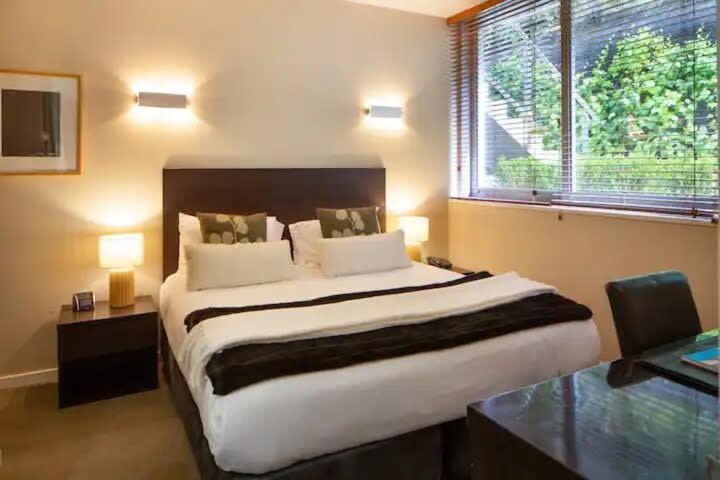 ein Schlafzimmer mit einem großen Bett und einem Fenster in der Unterkunft Stunning 1 Bedroom Studio Apartment in Queenstown