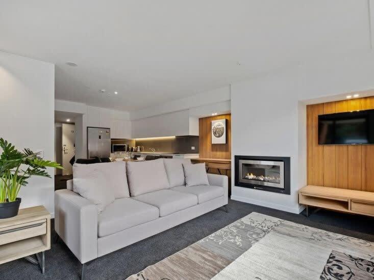 a living room with a white couch and a fireplace at Shotover Serenity in Queenstown