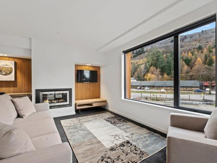 a living room with a couch and a large window at Shotover Serenity in Queenstown