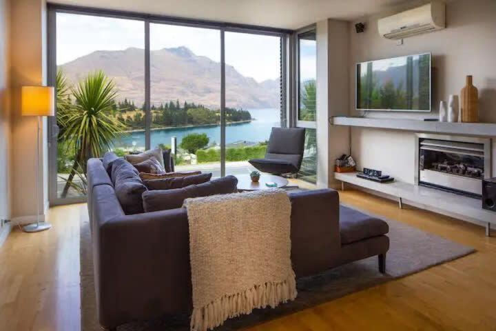 een woonkamer met een bank en een groot raam bij Stunning Lakeview 1 Bedroom Apartment in Queenstown