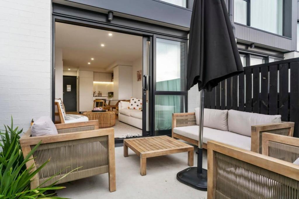 an outdoor patio with benches and an umbrella at Wanaka Riverside Townhouse Retreat in Albert Town