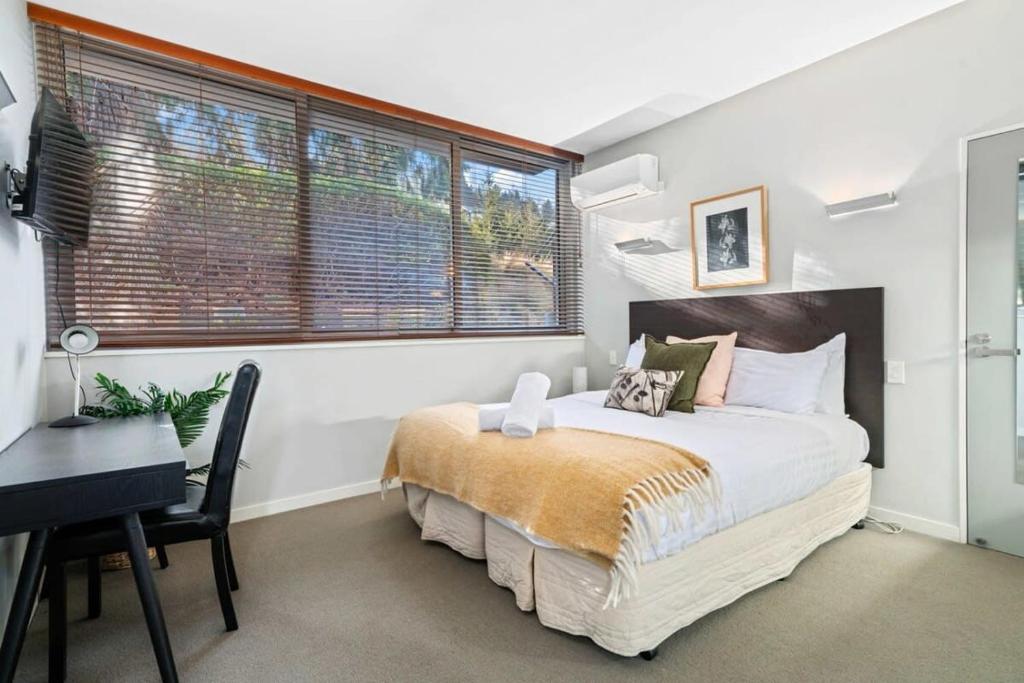 a bedroom with a bed and a desk and a window at Alpine Retreat Studio in Queenstown