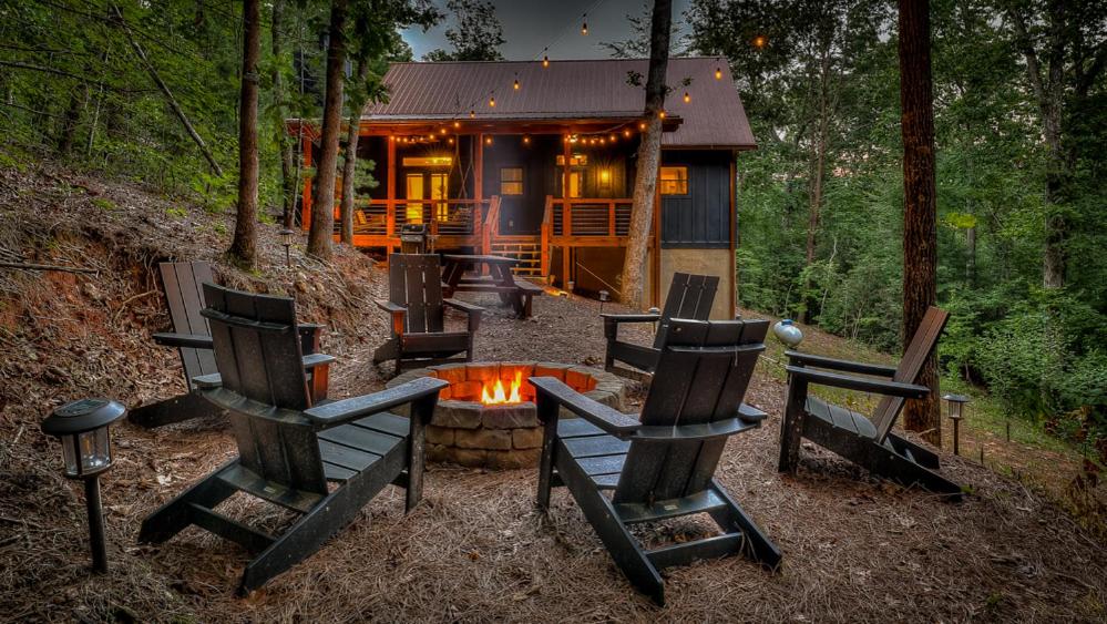 a cabin in the woods with chairs and a fire pit at Holiday House in Blue Ridge