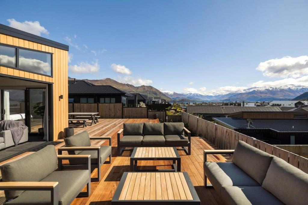 eine Dachterrasse mit Sofas, Tischen und Bergen in der Unterkunft Views from the Heights in Wanaka