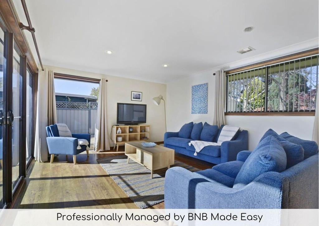 un soggiorno con divani blu e TV di Spacious Family Home - Leafy Suburb & Pets Allowed a Orange