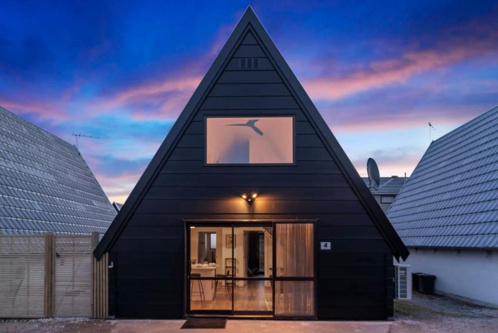 una casa negra con techo puntiagudo y ventana en MJ's Cottage Arrowtown, en Arrowtown