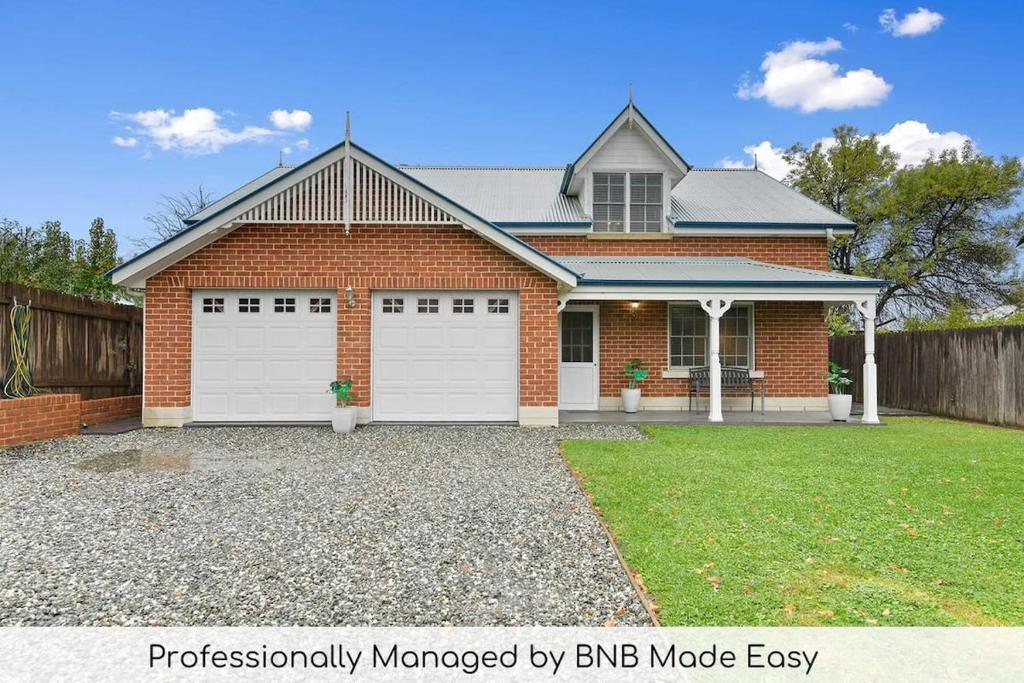 a brick house with two white garage doors at Peel St - Large Family Home Walk to CBD in Bathurst