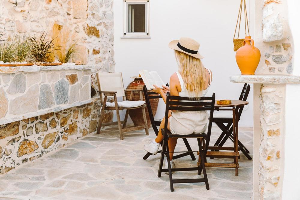 Laina Traditional Guest House في Apérathos: امرأة تجلس على كرسي على طاولة
