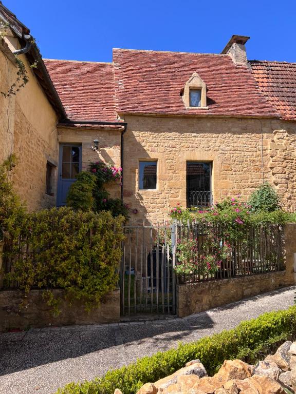 a brick house with a gate in front of it at Appartement de charme in Vitrac