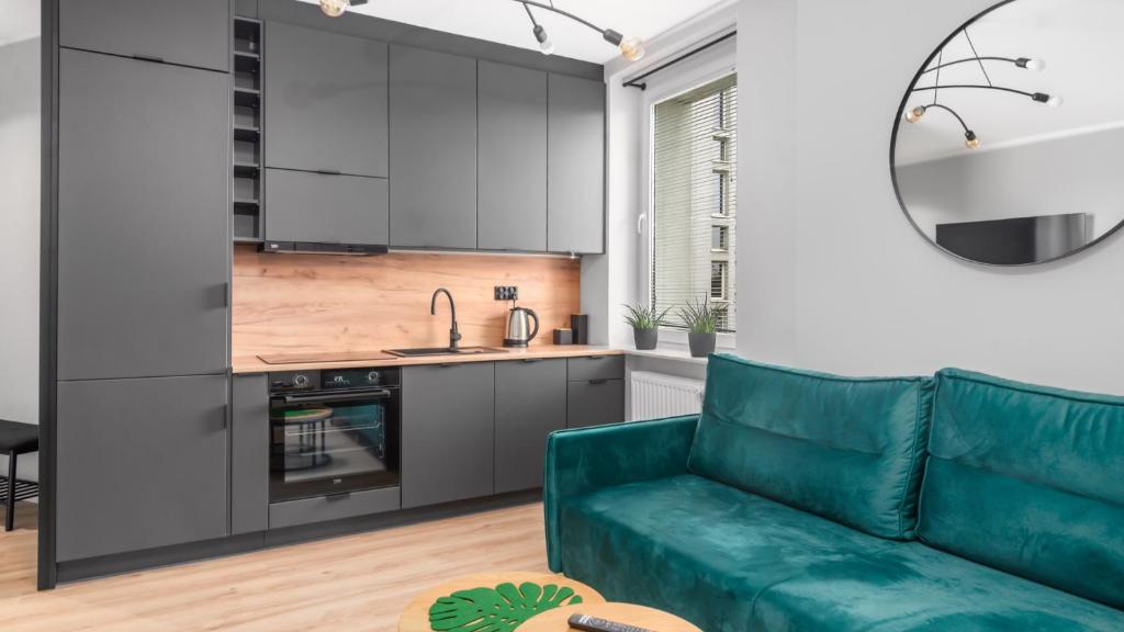 グディニャにあるUnique Apartments - Apartamenty w Centrum - Śląska 55のリビングルーム(緑のソファ付)、キッチンが備わります。
