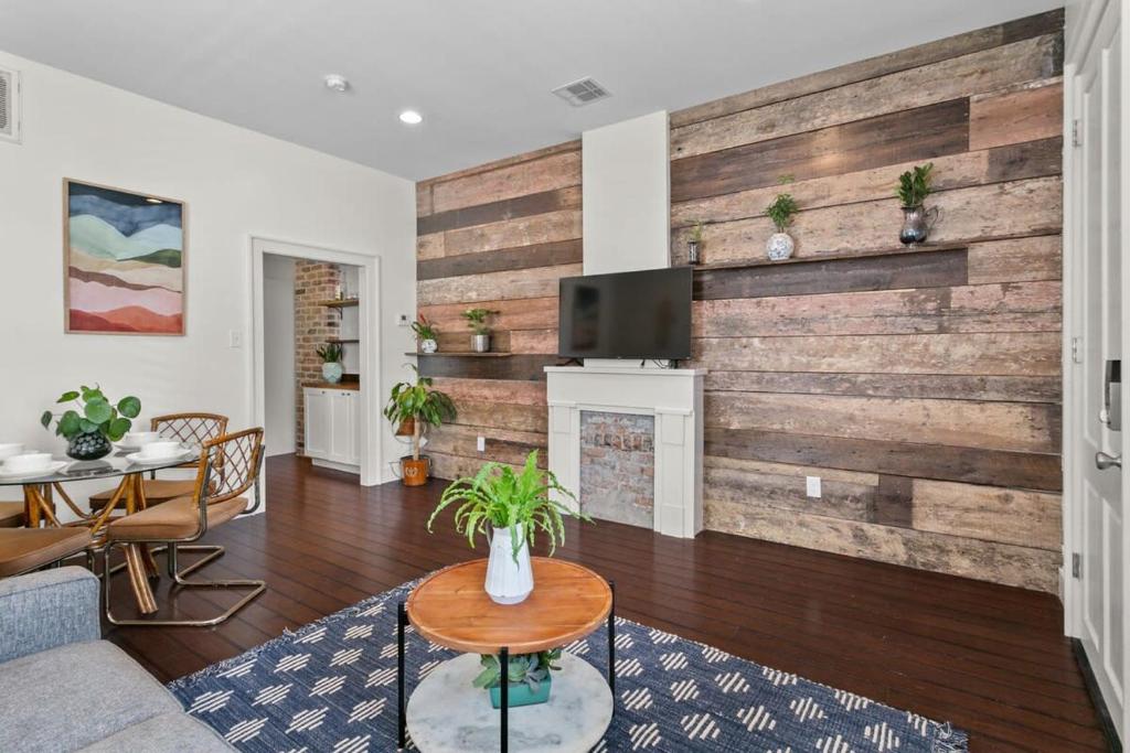 a living room with a wooden wall with a tv at Stylish Creole Cottage 1 BD Home Central Location in New Orleans