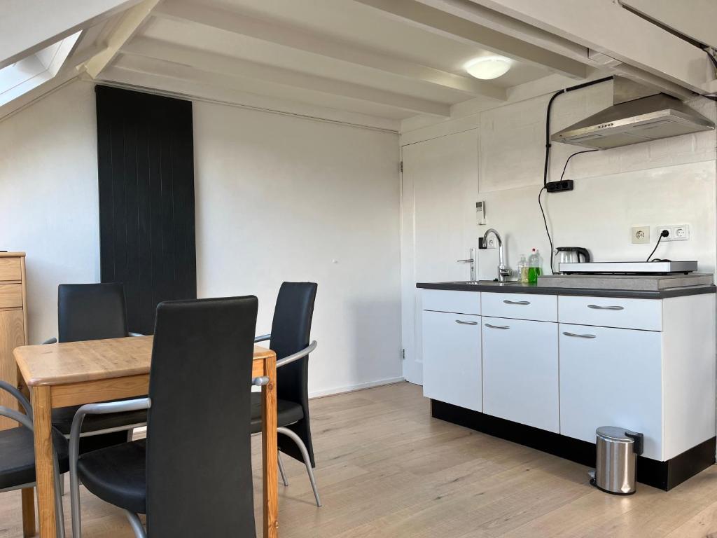 a kitchen and dining room with a table and chairs at Zolderstudio dichtbij Goffert met eigen badkamer en WC, eigen keuken, eigen ingang in Nijmegen