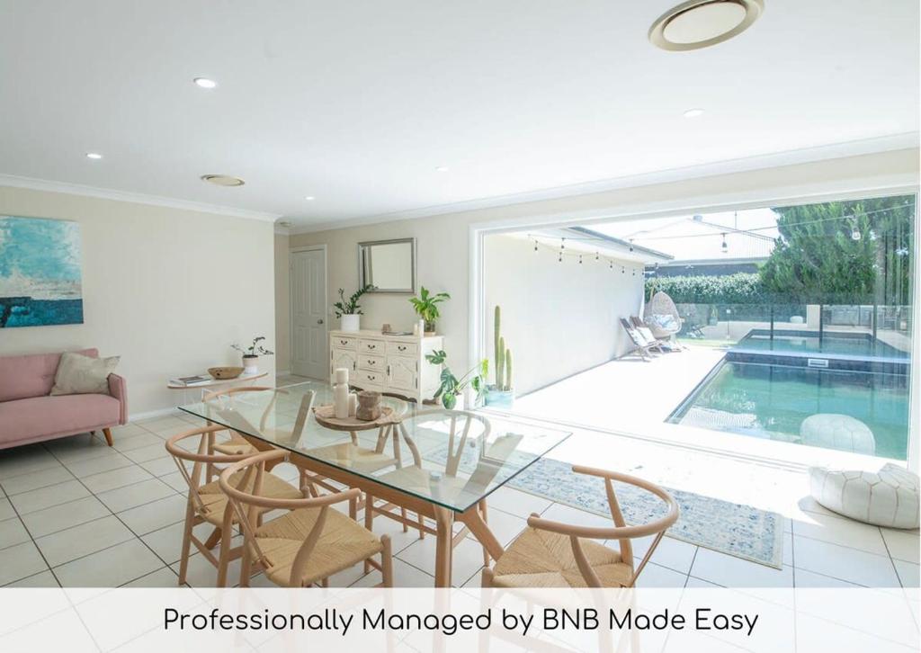 a living room with a glass table and a swimming pool at Regand Retreat - Pool, Luxurious Family Home in Dubbo