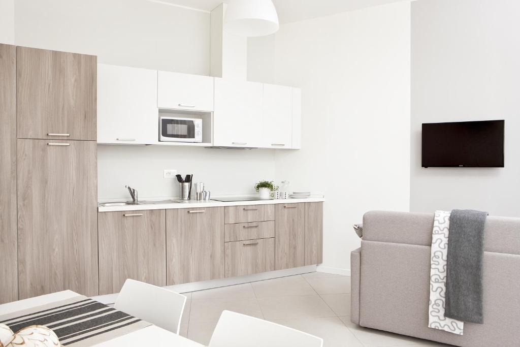 a white kitchen with a couch and a microwave at Palazzo Talenti 1907 in Trieste