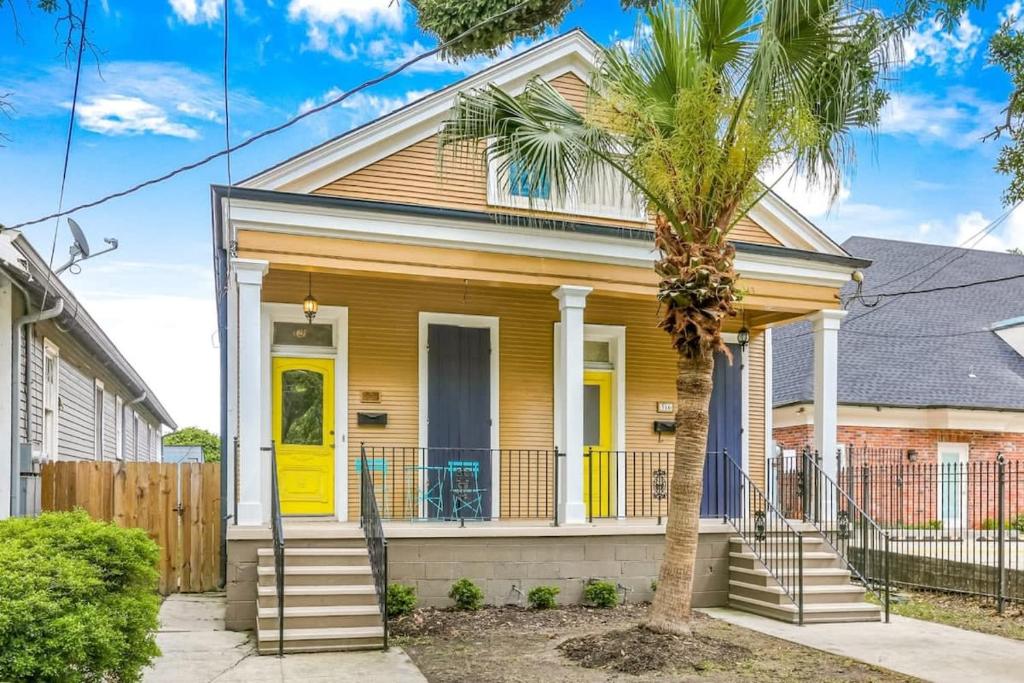 a yellow house with a yellow door and a palm tree at 5Bed StreetCar Retreat w Outdoor Entertaining in New Orleans