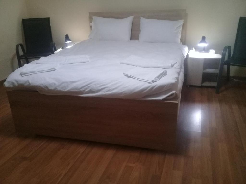 uma cama grande com lençóis brancos e almofadas em Villa Mukhrovani em Mukhrovani