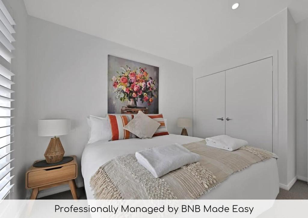 1 dormitorio con 1 cama y un jarrón de flores en The Elm Apartments - The Orange Room, en Orange
