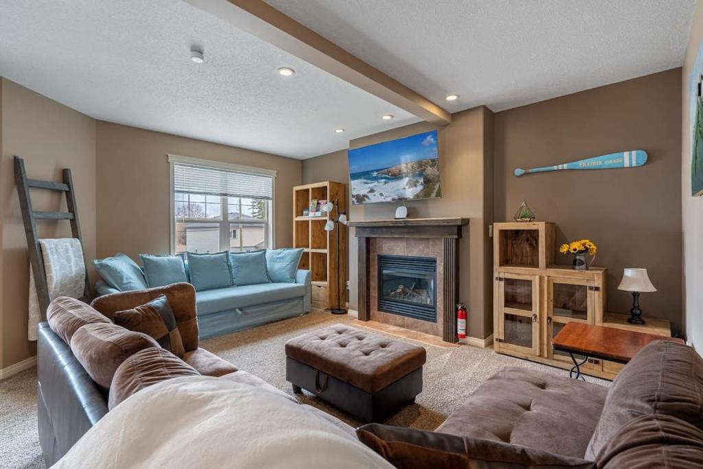 a living room with a couch and a fireplace at Prairie Oasis I Sleeps 16 l BBQ & Patio l Smart TV in Sylvan Lake