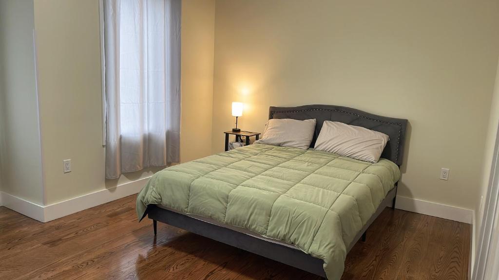 um quarto com uma cama com um edredão verde e uma janela em luxurious big house em Jersey City