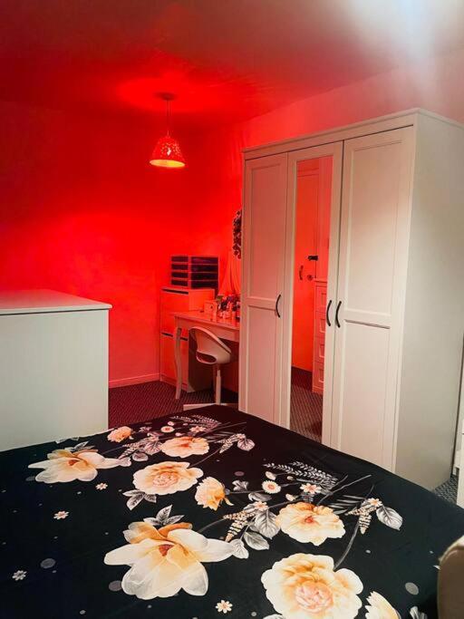 una habitación roja con una mesa con flores. en Luxury Top Quality natural Bedroom Near the Train Station, en Barking