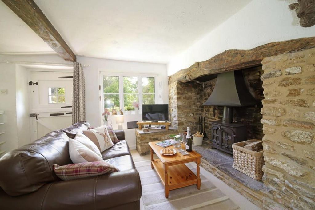 un soggiorno con divano in pelle e camino in pietra di Idyllic Cottage in Dorset Garden & Parking a Gillingham