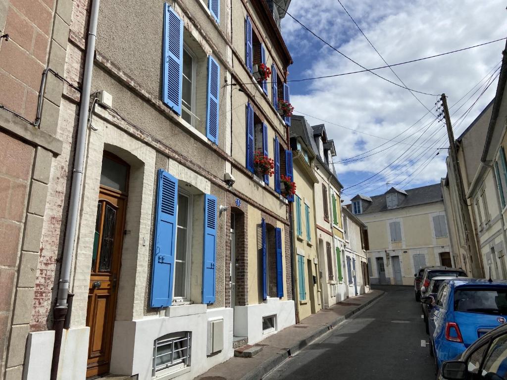 a street with buildings with blue shutters and cars parked at Maison de pêcheur Valentine à Trouville in Trouville-sur-Mer