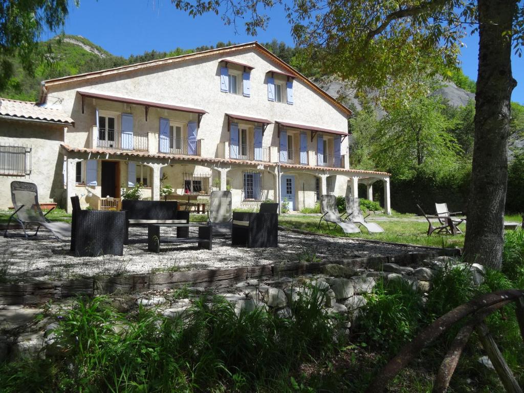 une grande maison blanche avec une table et des chaises dans l'établissement La Bergerie du Clot, à Val-de-Chalvagne