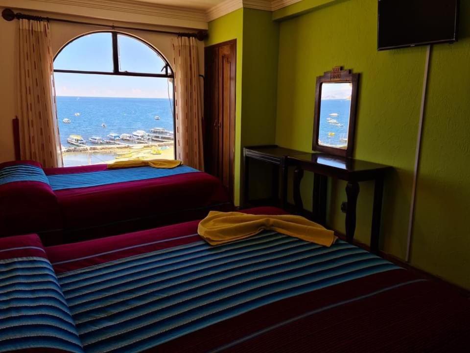 a room with two beds and a window with the ocean at HOTEL MIRADOR AL TITICACA in Copacabana