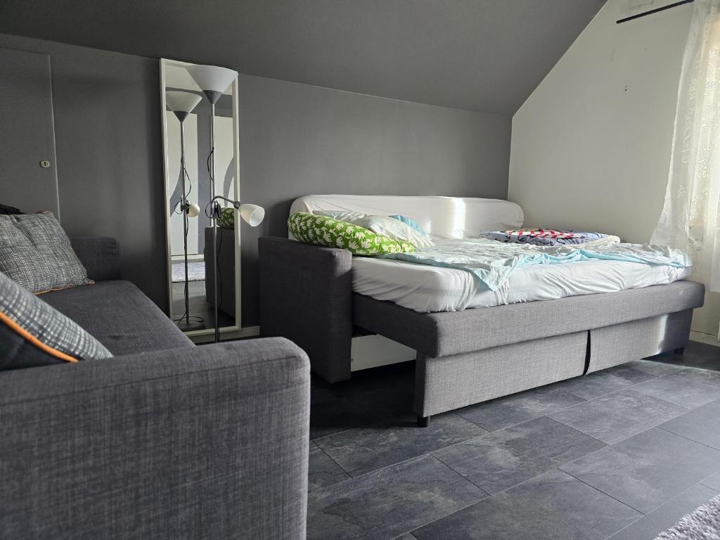 Bett in einem Zimmer mit Sofa und Spiegel in der Unterkunft hus,2 sovrum, 2 våning, 2 badrum in Simrishamn
