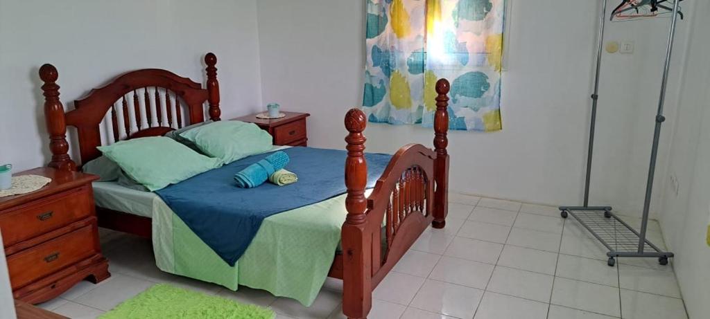 Schlafzimmer mit einem Holzbett mit blauer Bettwäsche und blauen Kissen in der Unterkunft Villa Léïna in Le Robert