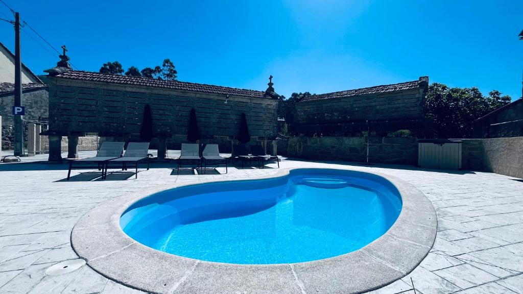 una gran piscina azul en un patio con sillas en Lar de Canedo en Carnota