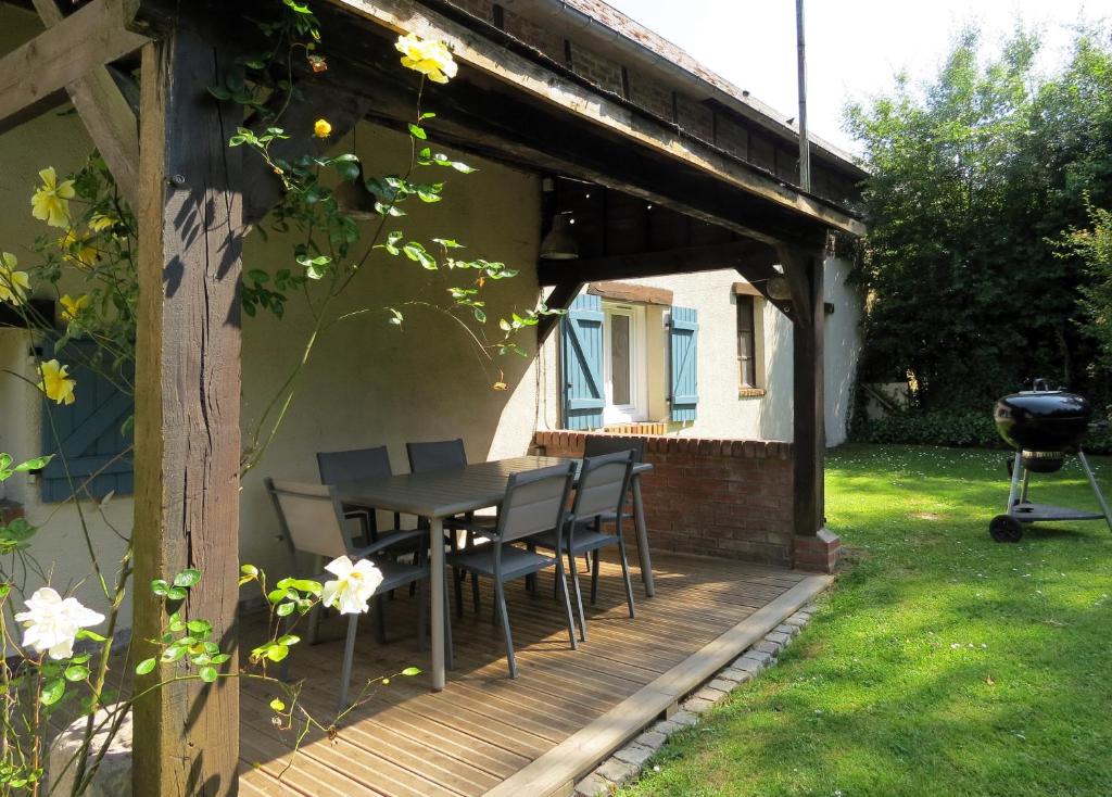 eine Holzterrasse mit einem Tisch und Stühlen darauf in der Unterkunft Le Gîte du Coin - Maison de vacances avec jardin in Le Bocasse