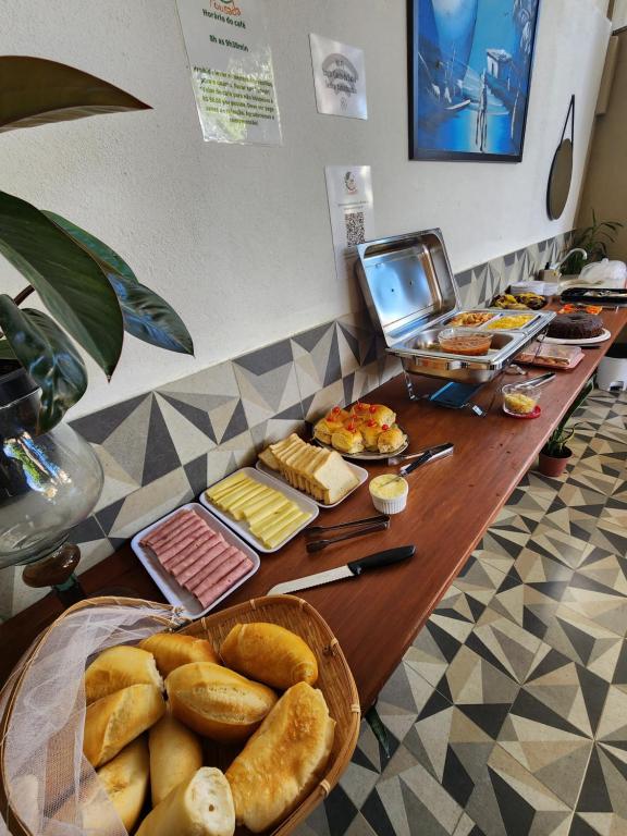 un buffet con pan y otros alimentos en una mesa en Pousada Canto do Sabiá en Piúma