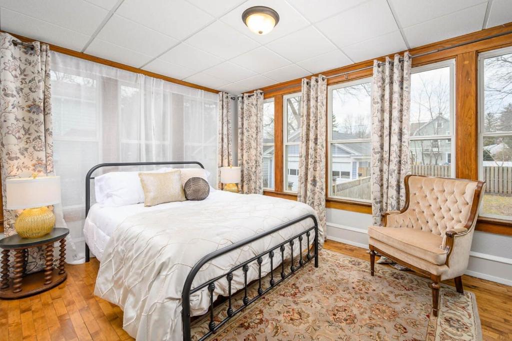 a bedroom with a bed and a chair and windows at Historic Heritage Haven in Appleton